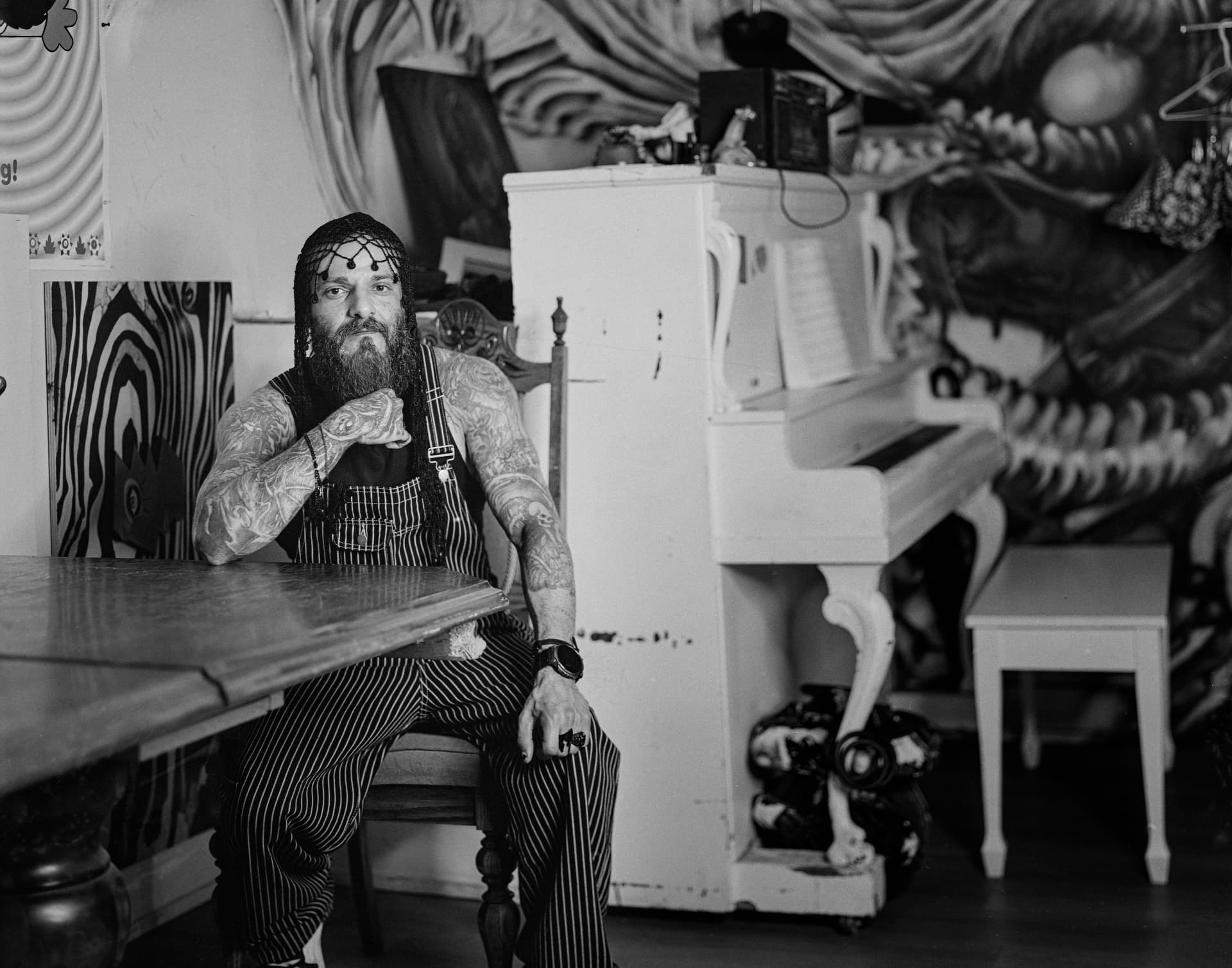 Tattooed artist seated beside a piano
